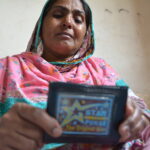 Nasra Bibi pleure en tenant dans ses mains le portefeuille de son fils, retrouvé dans l’usine Ali Enterprises où il est mort.