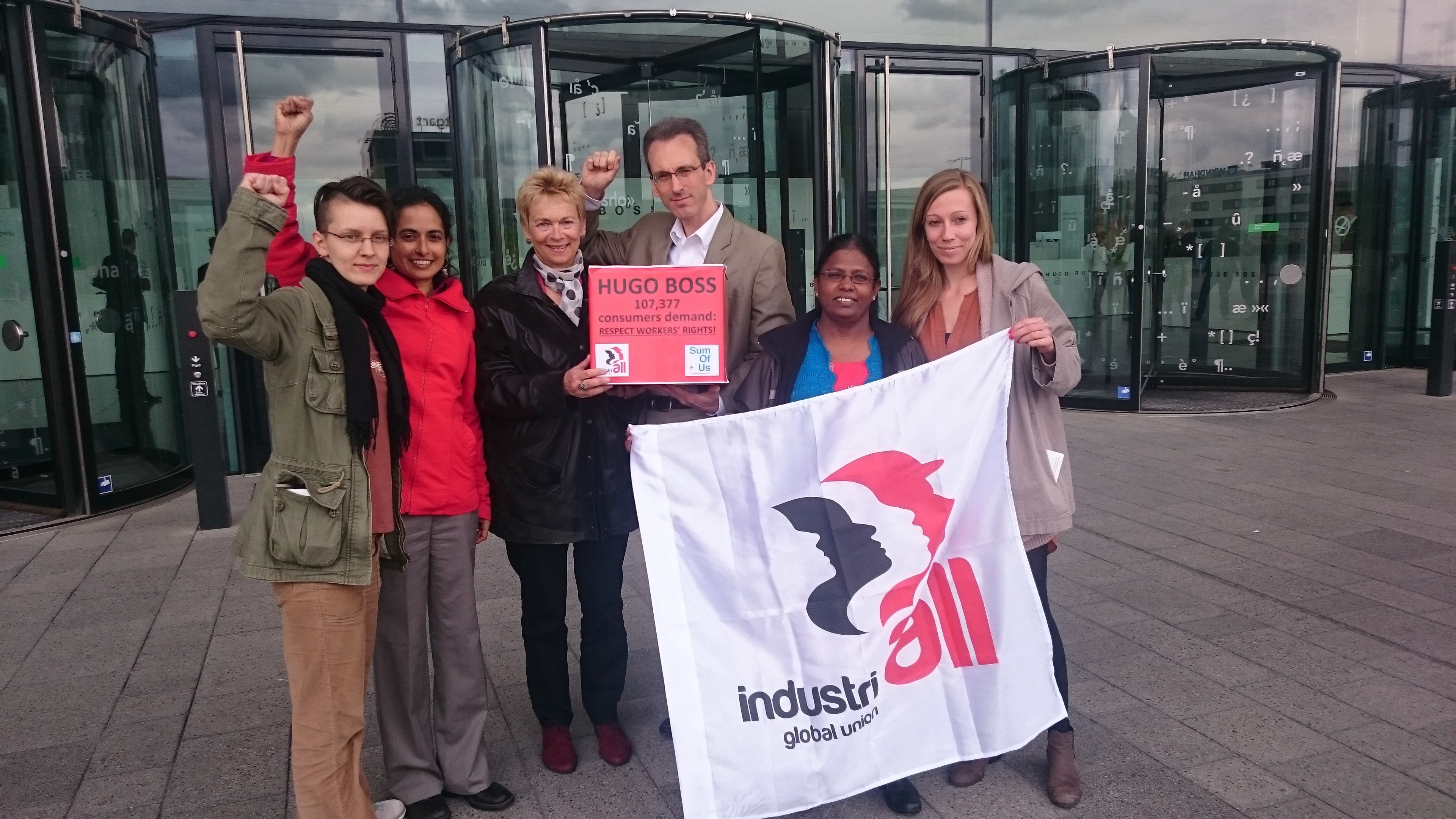 Директор IndustriALL по вопросам органайзинга и кампаний Адам Ли около здания, в котором проходило ежегодное собрание акционеров Hugo Boss в Штутгарте, держит петицию, подписанную более 100000 человек.