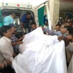 An injured worker is carried away to an ambulance.