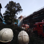 Workers watch as firefighters tackle the blaze.